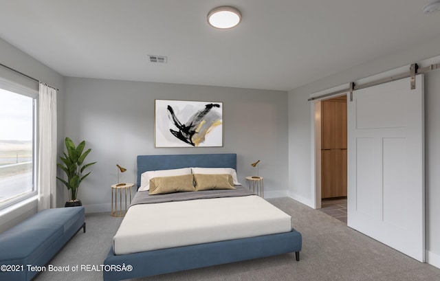 bedroom featuring multiple windows, a barn door, and carpet floors