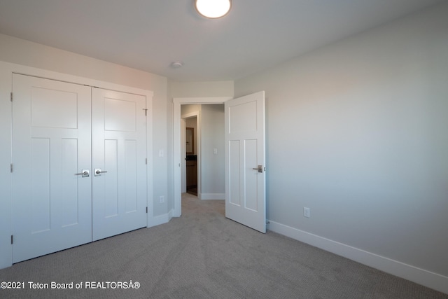 unfurnished bedroom with light carpet and a closet