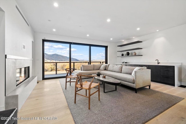 living room featuring bar area, a fireplace, a mountain view, and light wood-type flooring