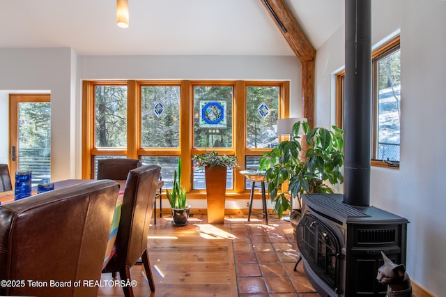 interior space with a healthy amount of sunlight, a wood stove, and beam ceiling