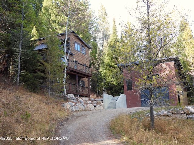 view of front of home featuring dirt driveway and a forest view