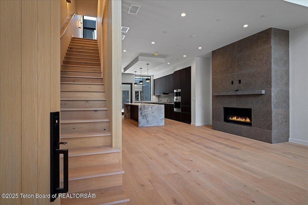 interior space with a tiled fireplace, sink, and light wood-type flooring