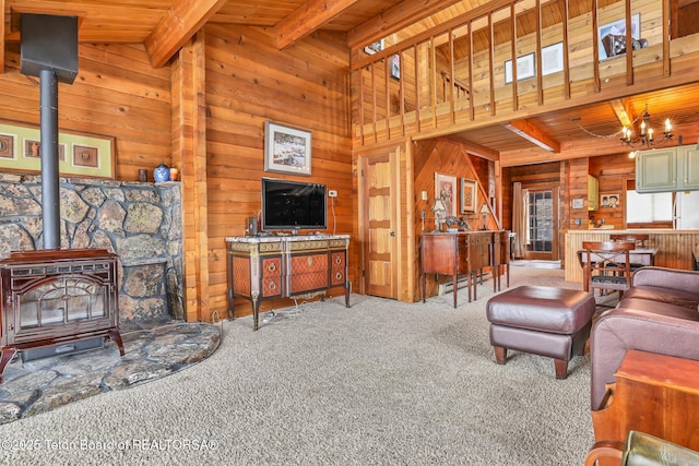 living room featuring a notable chandelier, carpet, wood walls, and a wood stove