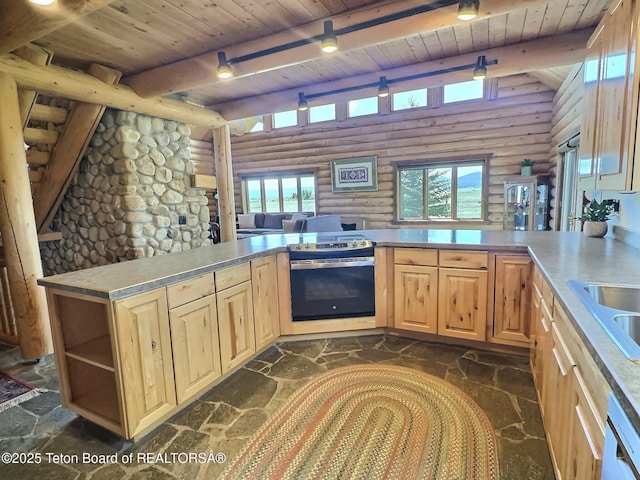 6352 W 1170 N, Driggs, ID 83442 - kitchen with log walls, stainless steel range with electric stovetop, wooden ceiling with exposed beams, light brown cabinetry, and stone flooring
