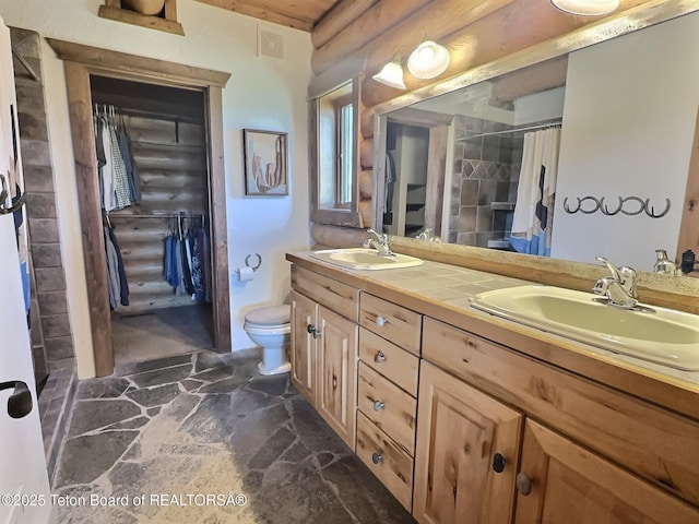 6352 W 1170 N, Driggs, ID 83442 - bathroom featuring stone floors, log walls, double vanity, toilet, and curtained shower