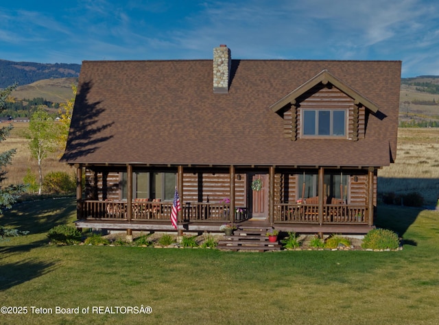 6352 W 1170 N, Driggs, ID 83442 - cabin with a chimney, a front yard, a deck with mountain view, a shingled roof, and log siding