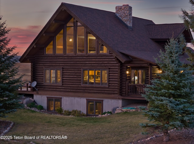 6352 W 1170 N, Driggs, ID 83442 - back of property at dusk with log exterior, a chimney, roof with shingles, a yard, and a deck