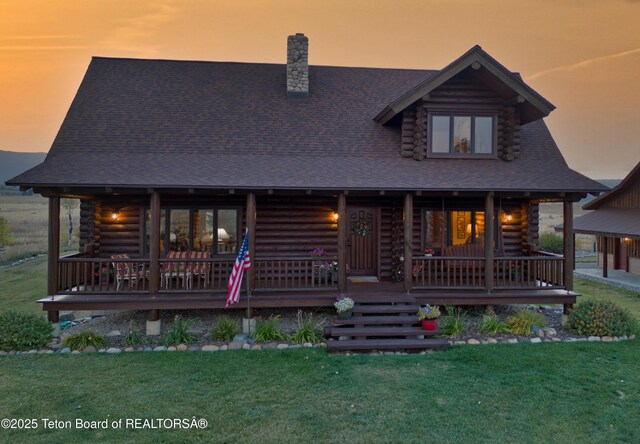6352 W 1170 N, Driggs, ID 83442 - log cabin with log siding, covered porch, a chimney, a yard, and a shingled roof