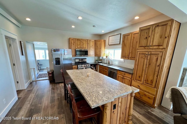 kitchen featuring a kitchen bar, light stone counters, a center island, a wealth of natural light, and stainless steel appliances