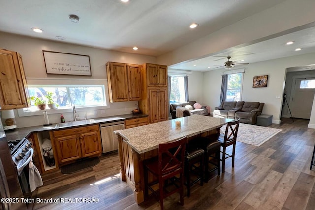 kitchen with a kitchen bar, sink, range with gas stovetop, dishwasher, and a kitchen island