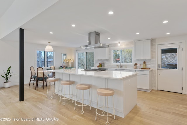 725 Cache Creek Dr, Jackson, WY 83001 - kitchen with white cabinetry, a spacious island, island range hood, and hanging light fixtures