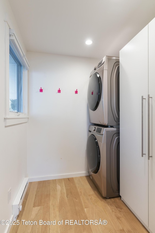 725 Cache Creek Dr, Jackson, WY 83001 - clothes washing area featuring stacked washing maching and dryer, a baseboard radiator, and light hardwood / wood-style flooring
