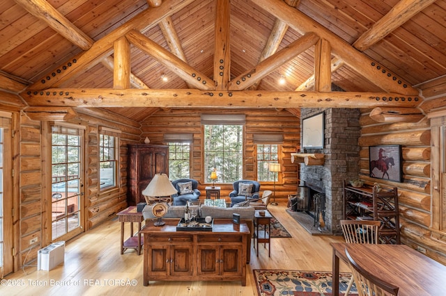 living room with beam ceiling, a stone fireplace, high vaulted ceiling, and light wood-type flooring