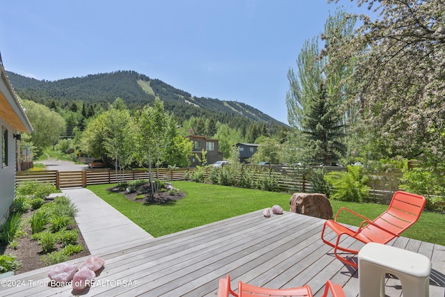 wooden deck with a mountain view and a lawn