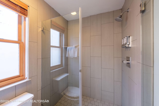 bathroom with a tile shower and toilet