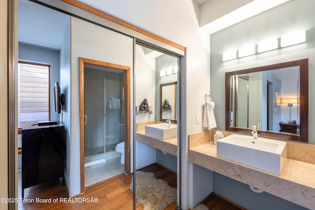 bathroom with hardwood / wood-style flooring, a shower with door, sink, and toilet