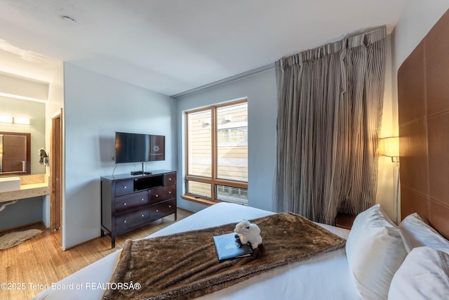 bedroom with ensuite bathroom and light hardwood / wood-style floors