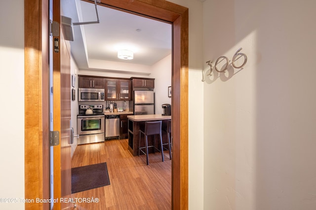 kitchen featuring dark brown cabinets, a kitchen breakfast bar, light hardwood / wood-style floors, and appliances with stainless steel finishes