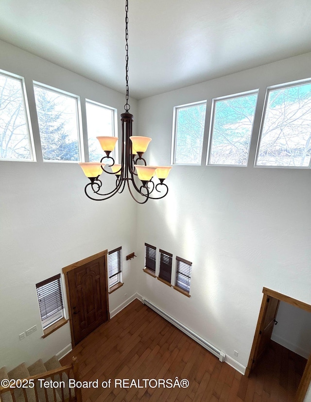 interior space with a wealth of natural light, baseboard heating, visible vents, and dark wood-style flooring