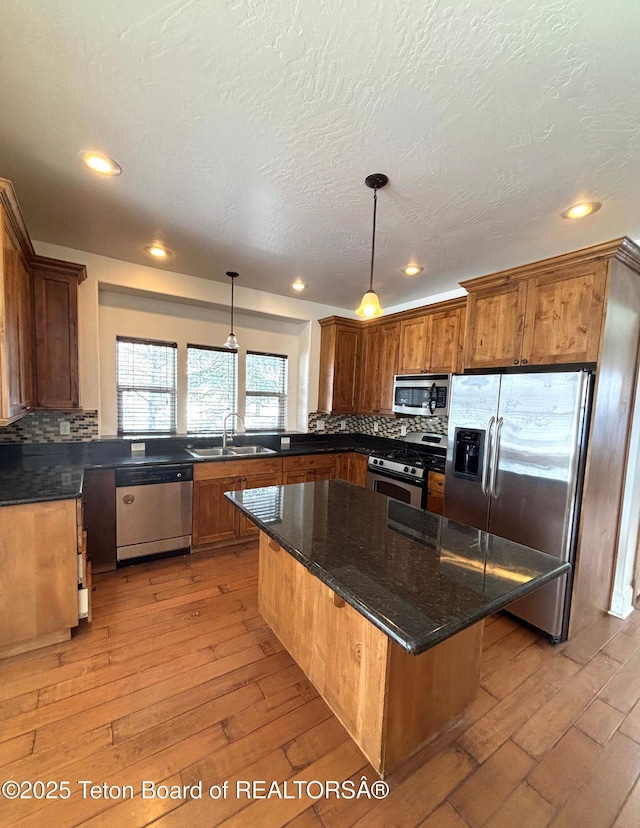 kitchen with decorative backsplash, appliances with stainless steel finishes, light wood-style floors, and a sink