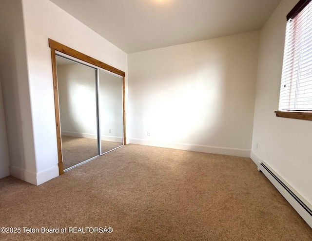 unfurnished bedroom featuring a closet, baseboards, a baseboard heating unit, and carpet