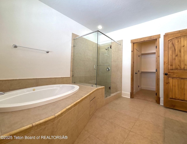 bathroom featuring tile patterned floors, a shower stall, baseboards, a bath, and a spacious closet