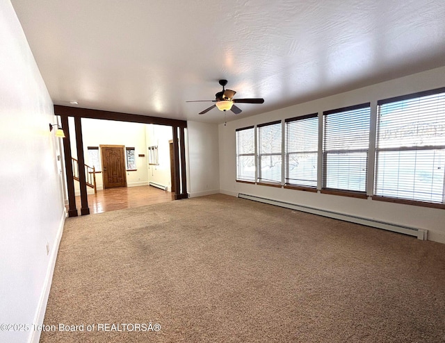 empty room with a baseboard heating unit, baseboards, carpet flooring, a ceiling fan, and a baseboard radiator