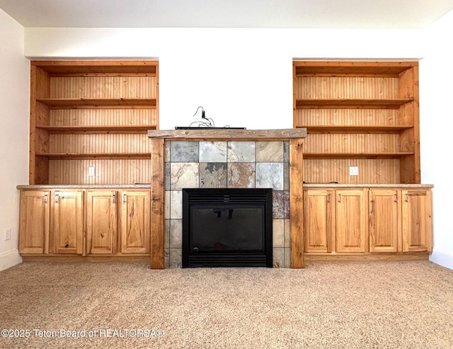 unfurnished living room with light carpet and a tiled fireplace