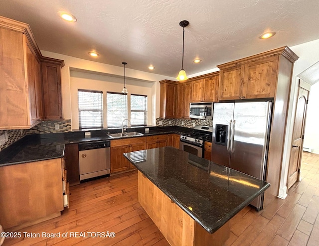 kitchen featuring a sink, light wood-type flooring, backsplash, and appliances with stainless steel finishes