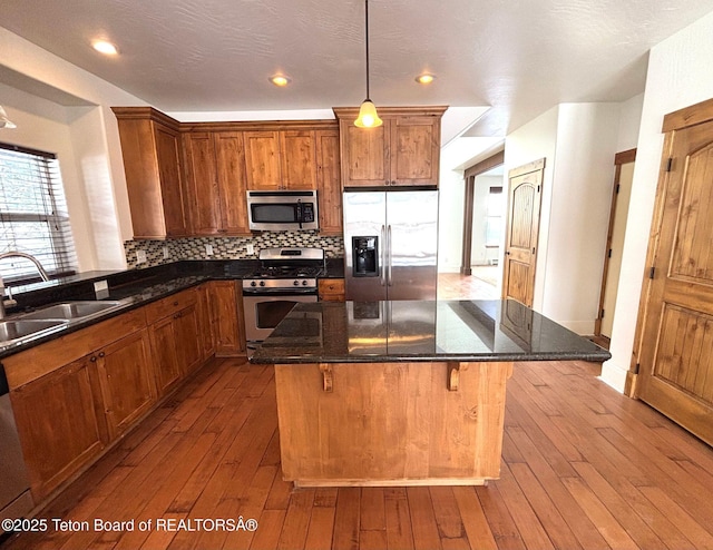 kitchen featuring hardwood / wood-style floors, decorative backsplash, appliances with stainless steel finishes, and a sink