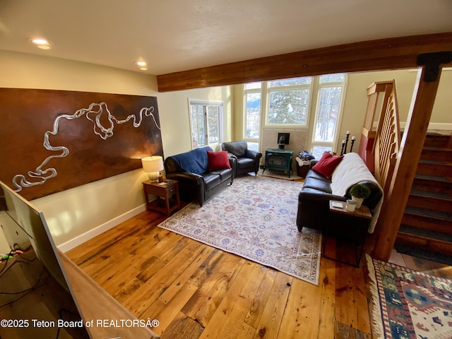 living room with baseboards, stairway, wood finished floors, a wood stove, and recessed lighting