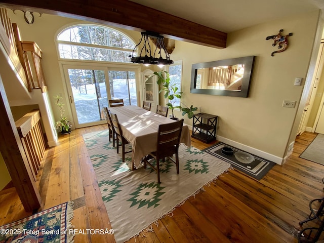 dining space featuring beam ceiling, light wood-style flooring, and baseboards