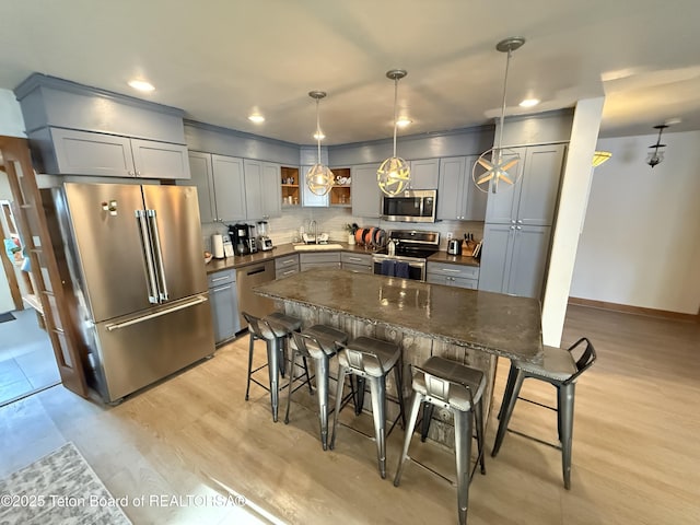 kitchen featuring tasteful backsplash, appliances with stainless steel finishes, decorative light fixtures, gray cabinets, and open shelves