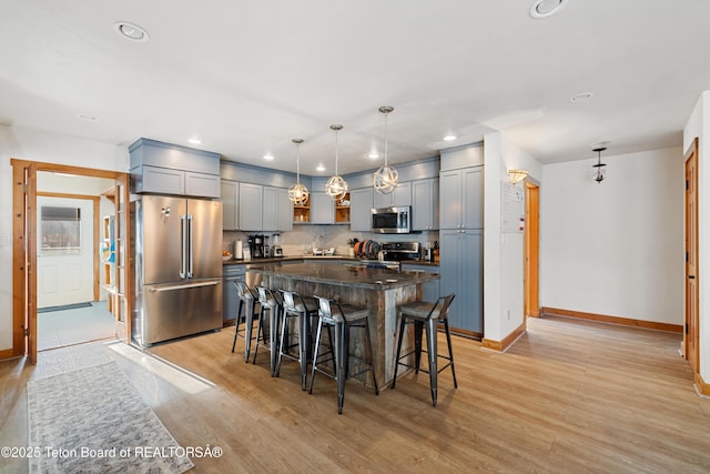 kitchen featuring decorative light fixtures, decorative backsplash, appliances with stainless steel finishes, light wood-style floors, and a kitchen island