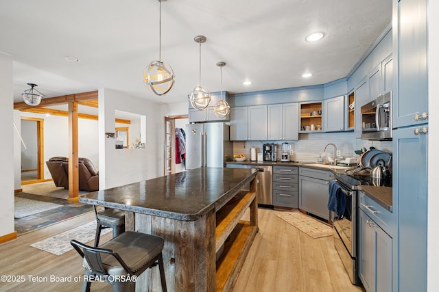 kitchen featuring stainless steel appliances, a center island, open shelves, dark countertops, and decorative light fixtures