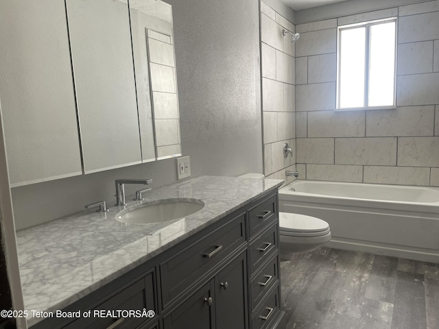 full bath with a textured wall, toilet, vanity, wood finished floors, and  shower combination