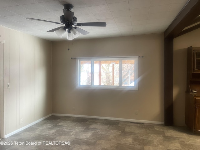 spare room with ceiling fan, baseboards, and stone finish floor