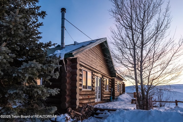 view of snowy exterior with log siding