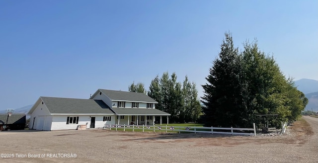 view of front of house featuring fence, an attached garage, and a mountain view