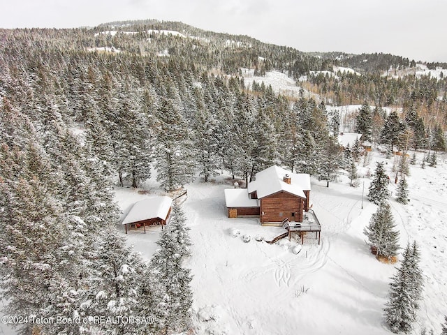 snowy aerial view featuring a mountain view and a wooded view