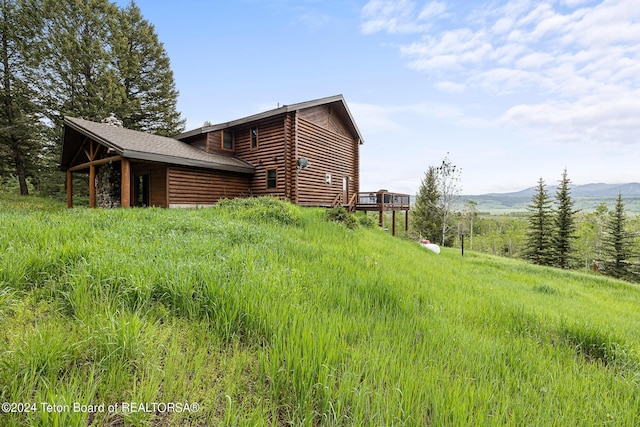 view of side of home with a deck with mountain view and log exterior