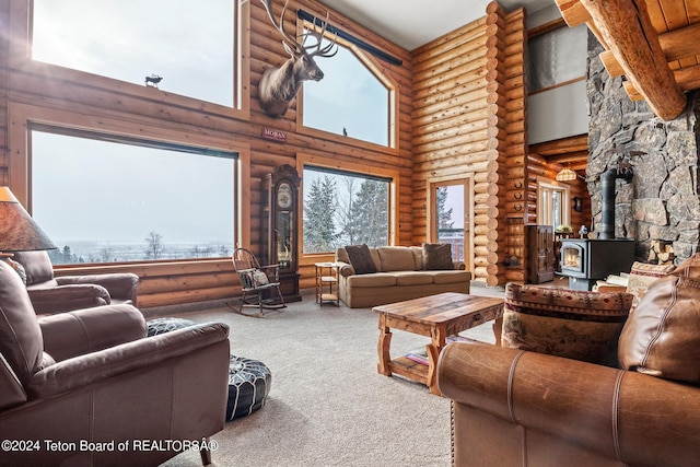 living area with a wood stove, carpet flooring, and a towering ceiling