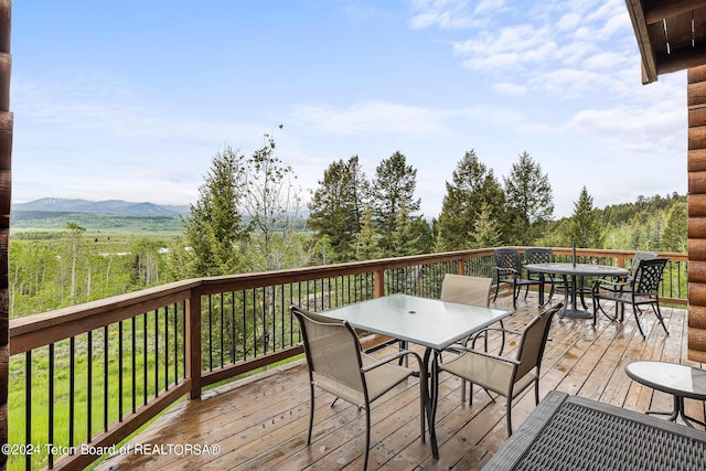 wooden terrace with outdoor dining area and a mountain view