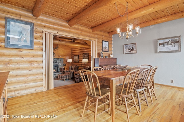 dining room featuring a stone fireplace, wood ceiling, baseboards, light wood-type flooring, and beamed ceiling