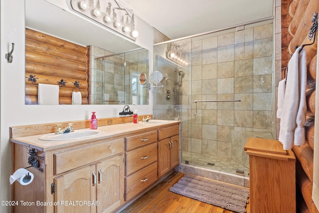 full bathroom featuring double vanity, wood finished floors, a sink, and log walls