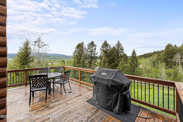 wooden deck with outdoor dining space and area for grilling