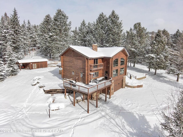 snow covered back of property featuring a garage and a chimney