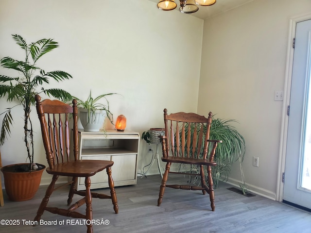 living area featuring visible vents, baseboards, and wood finished floors