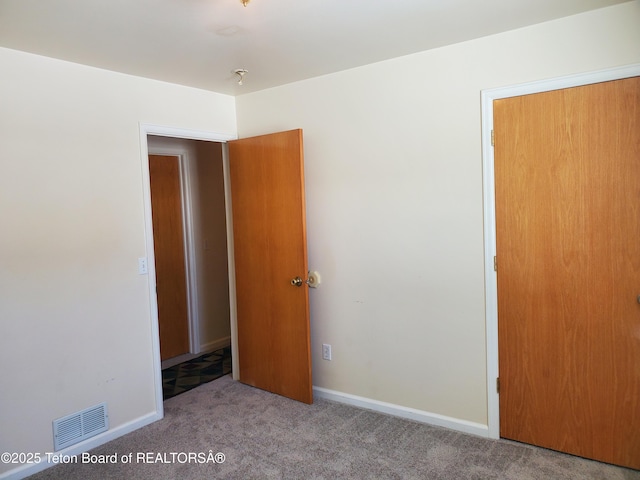 unfurnished bedroom featuring carpet, visible vents, and baseboards