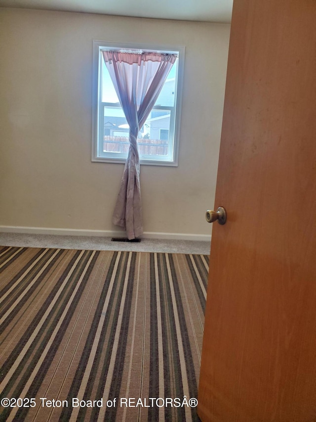 carpeted empty room featuring baseboards